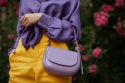 Pale Purple Faux Leather Trendy Small Bag, Handbag In Fashionable Woman`s Hand. Model Wearing Violet Blouse, Yellow Trousers. Copy, Empty Space For Text