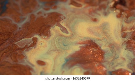Pale yellow, beige, golden ocher, glitter gold, copper and sienna colors mix. Fluid background. Real liquid oil paint. Marble texture in motion