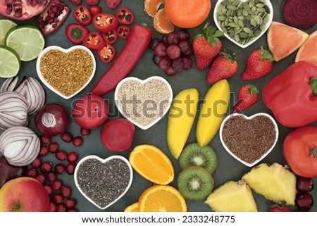Paleo diet health and super food of fruit, vegetables, nuts and seeds in heart shaped bowls on slate background, high in vitamins, anthocyanins, antioxidants, dietary fiber and minerals.