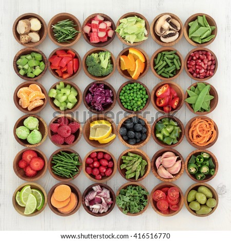 Paleolithic super health food of fruit and vegetables in wooden bowls over distressed white wood background. High in vitamins, antioxidants, minerals and anthocyanins.