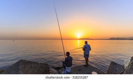 PALERMO, ITALY - SEPTEMBER 19 2015: Young And Older Italian Men Fishing In The Sunrise On Sicily