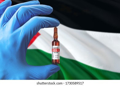 Palestine Flag With Coronavirus Covid-19 Concept. Doctor With Blue Protection Medical Gloves Holding A Vaccine Bottle. Epidemic Virus, Cov-19, Corona Virus Outbreaking.