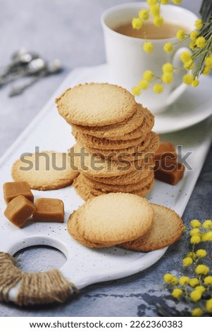 Palets bretons, french cookies. Salted caramel Shortbread Breton cookies, cup of coffee and bouquet of mimosa on light background. Focus selective