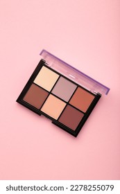 Palette of basic eyeshadows on pink background. Makeup concept. Top view