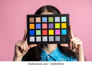Palette or colorchecker calibration in the hands of a girl. The model holds a color card in its hands for correct color transfer during further color correction.