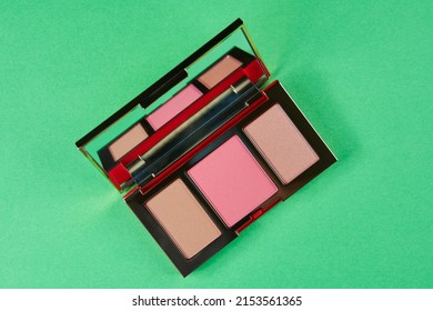 Palette For Contouring Close-up On A Green Background. Blush, Bronzer And Highlighter In A Gold Case