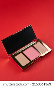 Palette For Contouring Close-up On A Red Background. Blush, Bronzer And Highlighter In A Gold Case