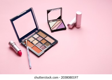 Palette of eyeshadows, brush and listicks on color background