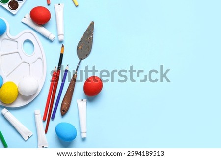 Palette knives, Easter eggs and brushes on color background