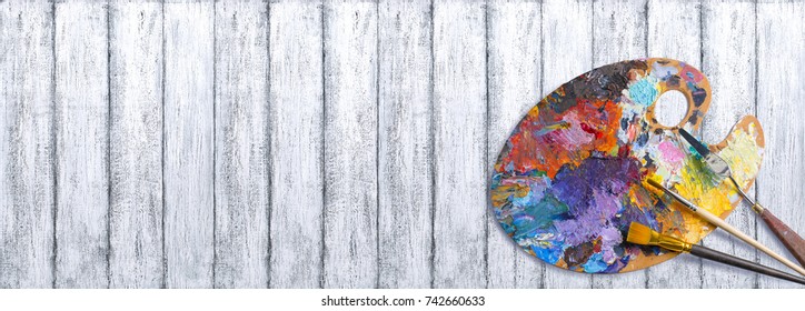 Palette for oil paints with brushes and palette knife on shabby wooden table - Powered by Shutterstock