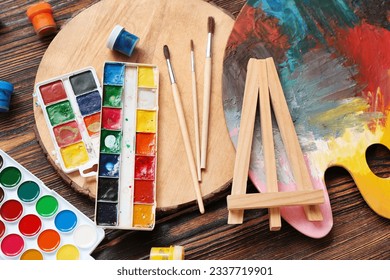 Palette with watercolor paints and brushes on wooden table - Powered by Shutterstock