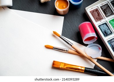 Palette Of Watercolor Paints, Cans With Color Tint, Brushes And  Paper On Table Background Ready For Drawing