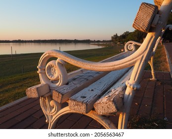 Palic, Serbia September 10, 2021. Metal bench overlooking Lake Palic. The seat is white. R letter on metal armrest. Golden hour in a quiet family resort. Tourist destination near the Hungarian border - Shutterstock ID 2056563467