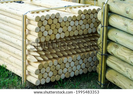 pallet with long round natural wooden fence posts with a sharpened tip