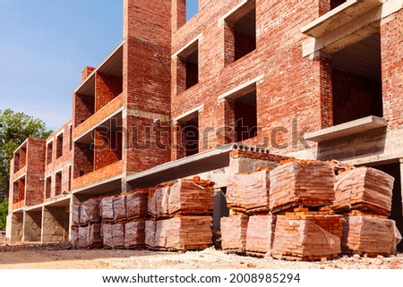 Pallets with bricks on a background of brick high-rise buildings.