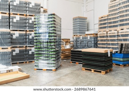 Pallets of empty and filled beer bottles and cans prepared for production or distribution in an industrial warehouse