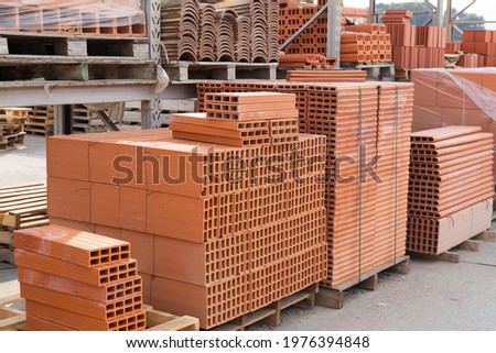 Pallets with stack of redbricks lying at warehouse of building materials in sunny day