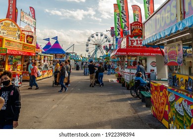 Palm Beach, Florida - USA - January 18, 2021 - The midway at the state and county fair with junk food vendors, amusement park games, ferris wheel, carnival rides and families enjoying the festival