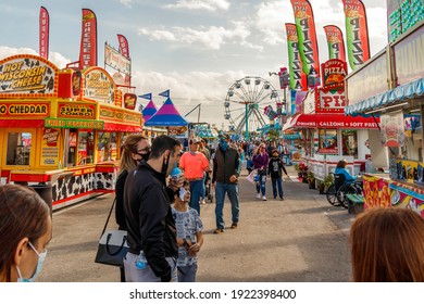 Palm Beach, Florida - USA - January 18, 2021 - The midway at the state and county fair with junk food vendors, amusement park games, ferris wheel, carnival rides and families enjoying the festival