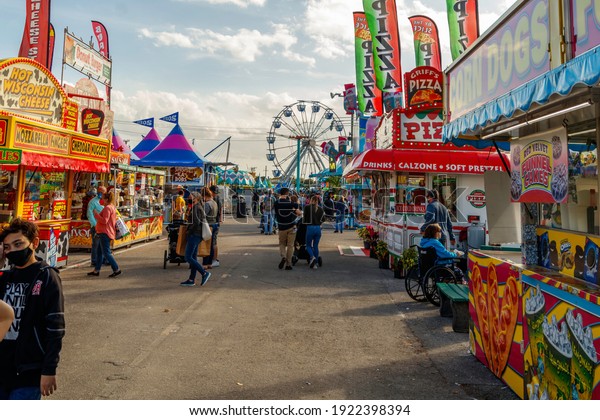 Palm Beach, Florida - USA - January 18, 2021 -\
The midway at the state and county fair with junk food vendors,\
amusement park games, ferris wheel, carnival rides and families\
enjoying the festival