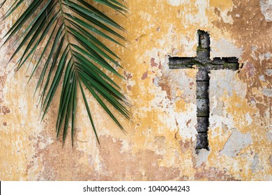 Palm branch and christian cross or crucifix on old vintage traditional wall as palm sunday religion and easter holiday concept background