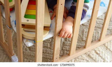 Palm hand of a small child in a wooden cot. Playing.