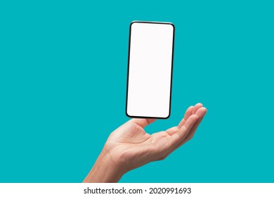 The Palm Of The Hand Supports The Floating Smart Phone, Isolate On Blue Green Background