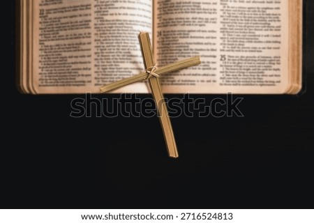 Palm leaf cross placed in open Bible with dark copy space, symbolizing Christian faith, Palm Sunday, Easter, worship and spiritual reflection, religion background for church, prayer, devotion concepts