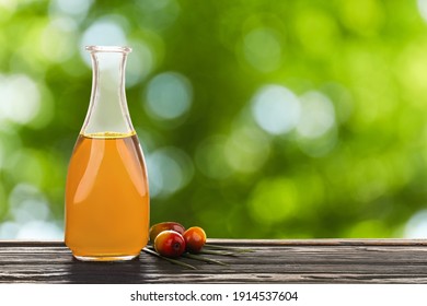 Palm Oil In Glass Bottle And Fruits On Wooden Table, Space For Text. Bokeh Effect  