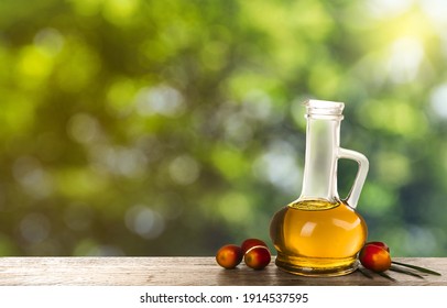 Palm Oil In Glass Jug, Tropical Leaf And Fruits On Wooden Table, Space For Text. Bokeh Effect 