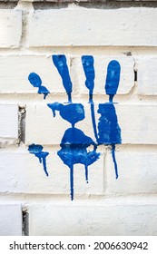 Palm Print Was Made In Blue Paint On A White Brick Wall. Great Idea. Abstract Background. 