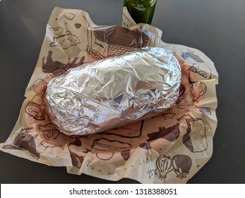 Palm Springs, California, United States - October 27, 2018: Chipotle Mexican Grill Burrito Wrapped In Tin Foil In A Basket With  Tabasco Sauce. With More Than 1600 Locations, Chipotle Had A Net Income