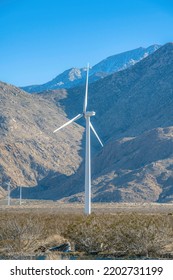 Palm Springs, California- Windmills On The Mountainside. Flat Field With Windmills Against The Mountain Slope And Skyline Background.