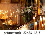 Palm Sunday. candles burn in an Orthodox church in front of the icon, against the background of willow and flowers