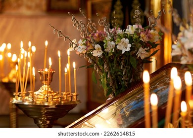Palm Sunday. candles burn in an Orthodox church in front of the icon, against the background of willow and flowers