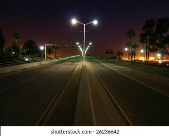 Palm Trees Line An Open California Highway At Night.