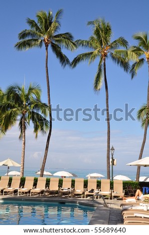 Palm trees and pool in front of ocean at  a famous historic hotel - on the island of Oahu along Waikiki beach built in 1901.