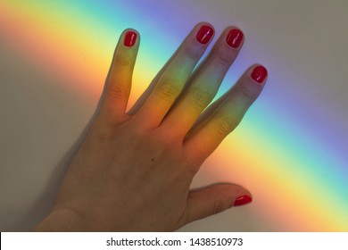 palm woman's hand and red nail polish rainbow background