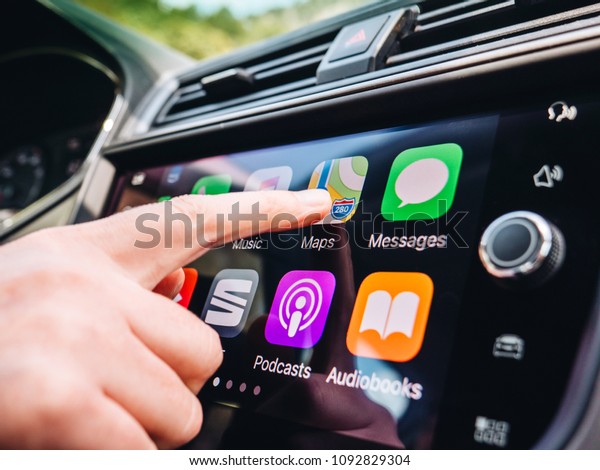 PALMA DE MALLORCA,\
SPAIN - MAY 10, 2018: Woman pressing Apple Maps button on the Apple\
CarPlay main screen in modern car dashboard during driving on\
Spanish holiday highway 