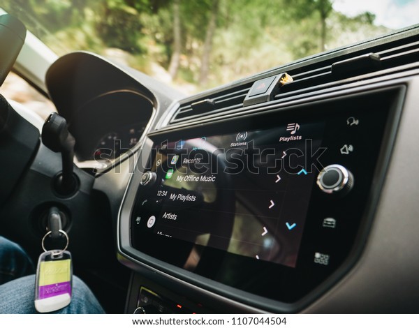PALMA DE MALLORCA, SPAIN - MAY 10,\
2018: Woman pressing button on the Apple CarPlay main screen in\
modern car dashboard during driving with Amazon Music app\
