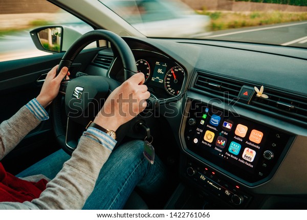 Palma de Mallorca, Spain - May 8, 2018: Young adult\
woman driving fast on spanish Highway at dusk a Seat car using\
Apple Car iOS with multiple applications such as Amazon music,\
Audible, Deezer, Maps