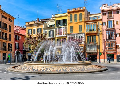 PALMA, SPAIN - APRIL 12, 2019: Fountain and colorful building on Plaza de la Reina - one of the famous and popular places located in the historical and tourist centre of Palma de Mallorca.