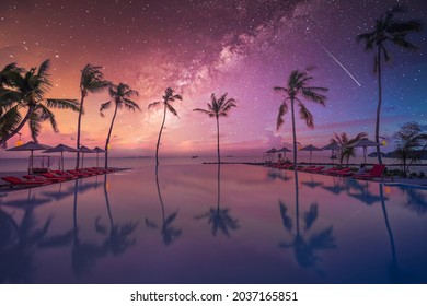 Palms chairs around infinity swimming pool near sea ocean with palm trees beach at night sunset time. Lifestyle leisure carefree travel vacation, summer resort landscape. Fantasy nature landscape