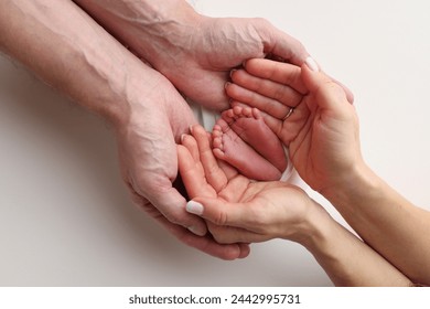 The palms of the father, the mother are holding the foot of the newborn baby in a white blanket. Feet of the newborn on the palms of the parents. Studio macro photo of a child's toes, heels and feet. - Powered by Shutterstock