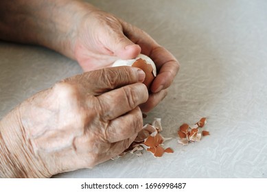 The palms of the hands of an elderly woman who peels a chicken egg from the shell. - Shutterstock ID 1696998487
