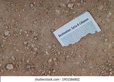 Palmyra, Syria 04-02-2010: A Torn Page From Lonely Planet's Travel Guide Book That Says Destination Syria And Lebanon Is Left Behind On The Desert By Tourists Visiting The Ruins Of Palmyra. 