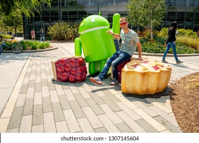 Palo Alto, USA. September 10, 2018. Young Man Sitting At The Google Office Near The Huge Android Sign In The Silicon Valley.