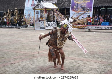 Pampang, East Borneo - June, 01 2022: A Dayak Dancer Performing The Kancet Pepatai Dance Using A Shield And Mandau Sword As Dance Accessories