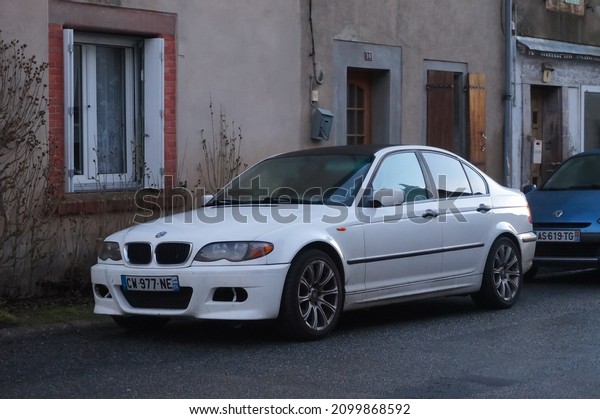 Pampelonne, France - Dec. 2021 - A white, 2006 BMW 3\
Series E46 parked on the curbside of the street, along a house wall\
: the model is a luxury sedan car produced by the German car\
manufacturer BMW