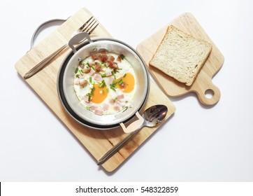 Pan fried eggs topping with sausage, bacon and ham is the breakfast, eat with sliced bread, May be called Vietnamese Omelet on chopping wood.